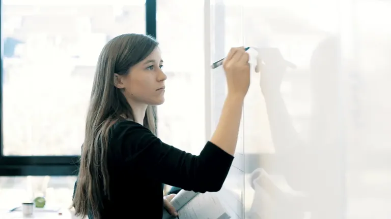 Kursleiterin schreibt eine Aufgabe an das Whiteboard